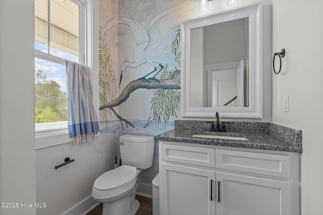 half bath featuring vanity, baseboards, and toilet