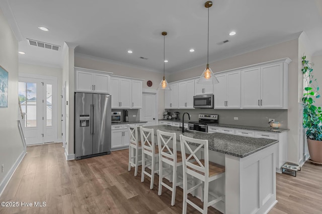 kitchen featuring an island with sink, white cabinets, a breakfast bar, and stainless steel appliances
