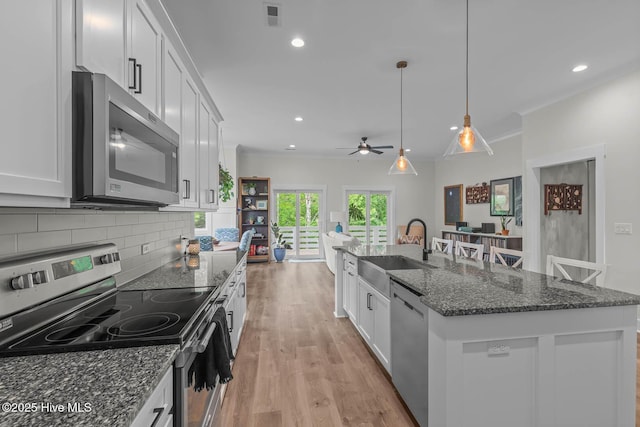 kitchen with visible vents, a sink, white cabinets, stainless steel appliances, and light wood-style flooring