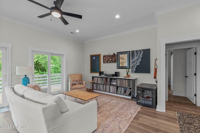 living area with crown molding, wood finished floors, baseboards, ceiling fan, and recessed lighting