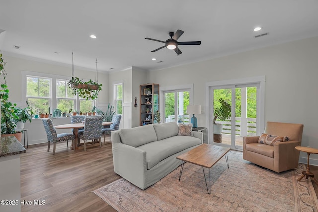 living area featuring visible vents, ceiling fan, wood finished floors, and a healthy amount of sunlight