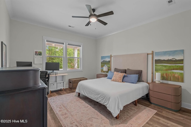 bedroom featuring ceiling fan, baseboards, visible vents, and wood finished floors