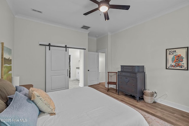 bedroom with crown molding, visible vents, and a barn door