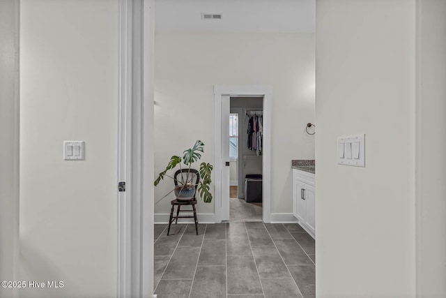hallway featuring baseboards and visible vents