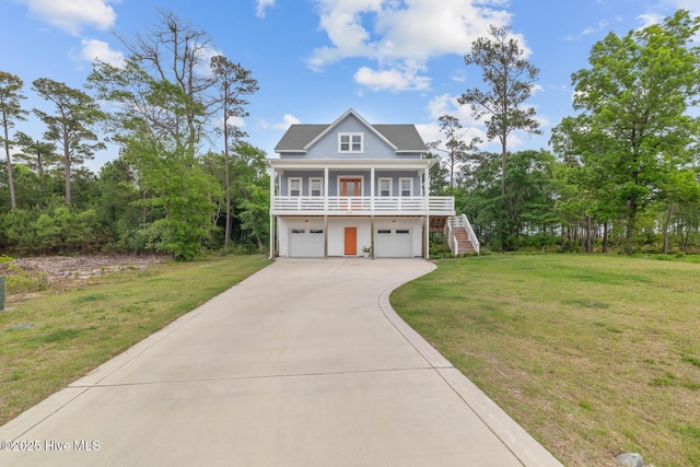 raised beach house with concrete driveway, a front lawn, stairs, and a garage