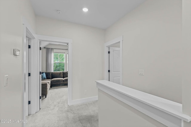 hallway with light colored carpet, recessed lighting, and baseboards