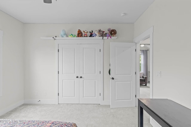 unfurnished bedroom with baseboards, light carpet, and a closet