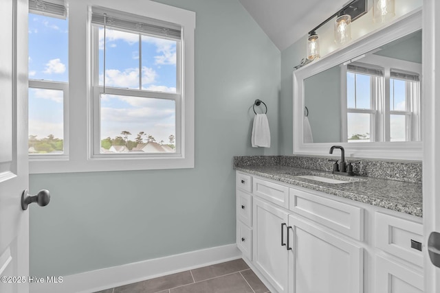 bathroom featuring baseboards, vaulted ceiling, tile patterned flooring, and vanity
