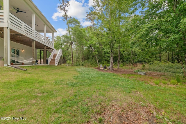 view of yard featuring a ceiling fan, stairway, and a deck
