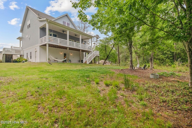 back of house with stairs, a ceiling fan, a wooden deck, and a yard