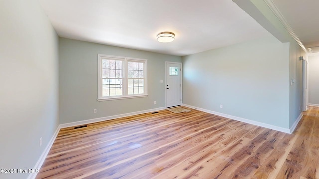 spare room featuring baseboards, light wood-style floors, and visible vents