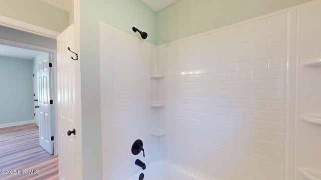 bathroom with baseboards, tub / shower combination, and wood finished floors