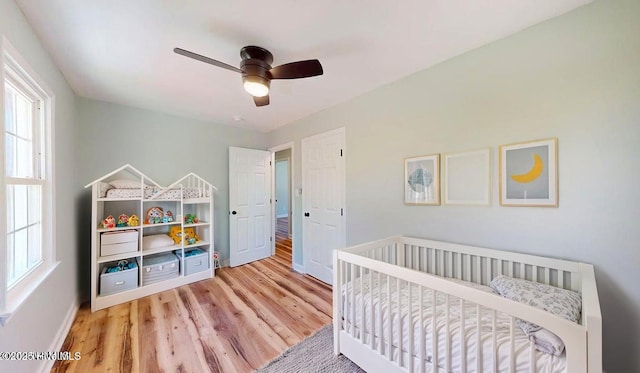 bedroom featuring multiple windows, wood finished floors, baseboards, and ceiling fan