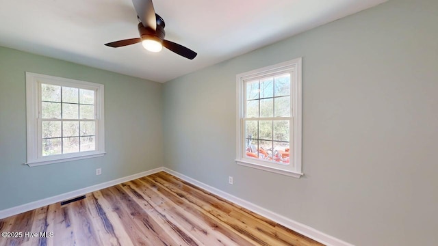 spare room featuring visible vents, baseboards, plenty of natural light, and wood finished floors