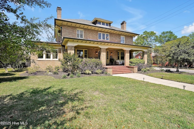 american foursquare style home with brick siding, a front yard, a porch, and a chimney
