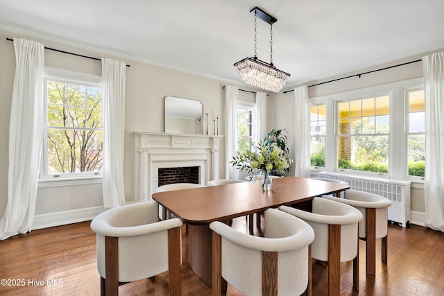 dining area with dark wood-type flooring, crown molding, a fireplace, and baseboards