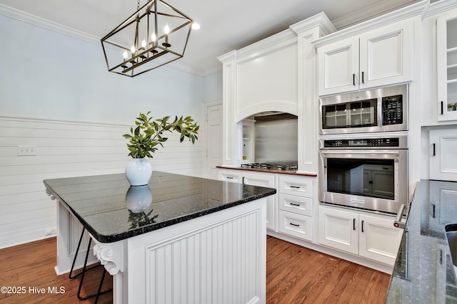 kitchen with a center island, appliances with stainless steel finishes, crown molding, white cabinetry, and light wood finished floors