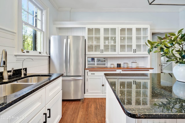kitchen featuring wood finished floors, freestanding refrigerator, a sink, and ornamental molding