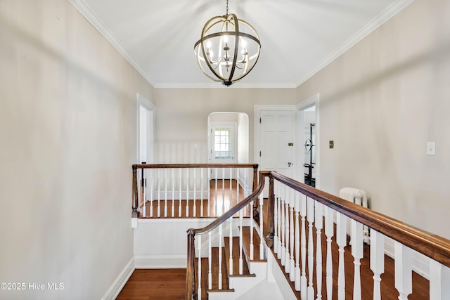 stairs featuring crown molding, wood finished floors, an inviting chandelier, and baseboards