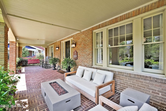 view of patio with a porch and an outdoor living space with a fire pit