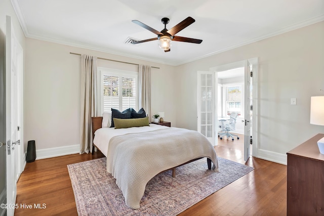 bedroom with crown molding, wood finished floors, baseboards, and visible vents