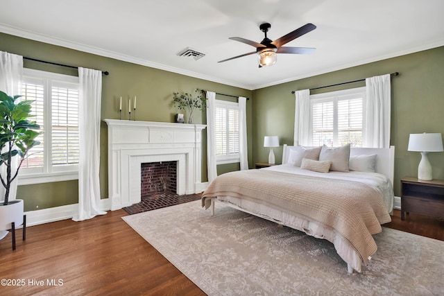bedroom with wood finished floors, ornamental molding, multiple windows, and visible vents