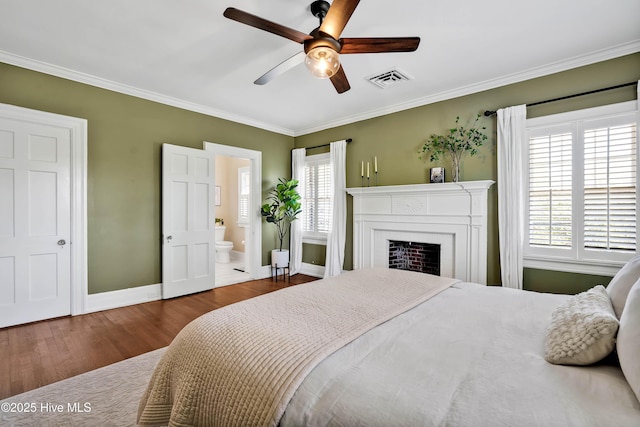 bedroom featuring visible vents, baseboards, a fireplace, crown molding, and wood finished floors