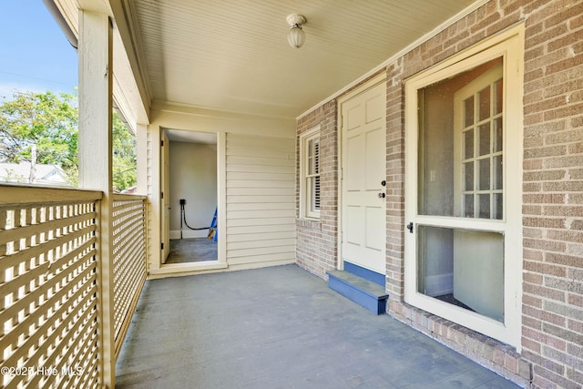 entrance to property featuring brick siding and covered porch