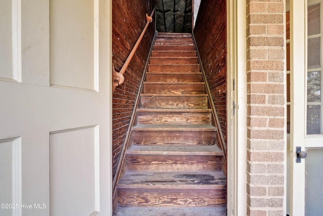 staircase featuring brick wall