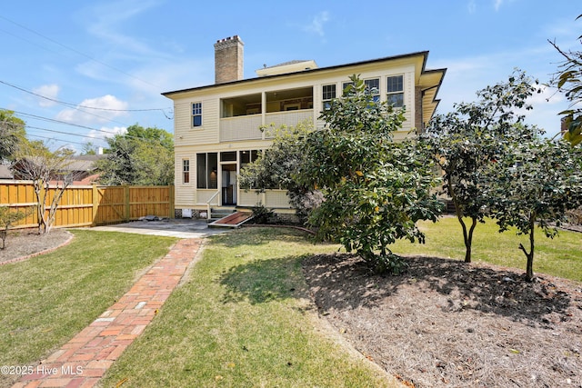 rear view of property featuring a sunroom, a lawn, a chimney, fence, and a balcony