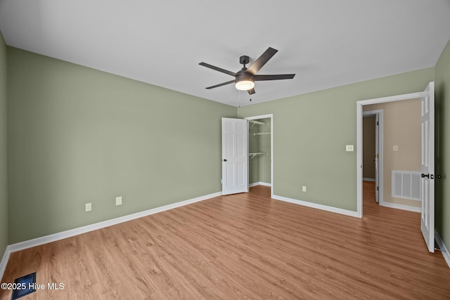 301 Pine Crest Rd, Trent Woods, NC 28562 - unfurnished bedroom featuring wood finished floors, baseboards, ceiling fan, a closet, and a walk in closet