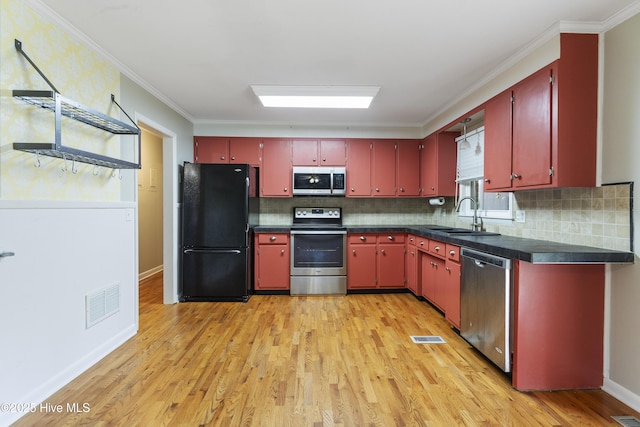 117 Brookfield Dr, Wilmington, NC 28405 - kitchen featuring stainless steel appliances, a sink, red cabinets, light wood-type flooring, and ornamental molding