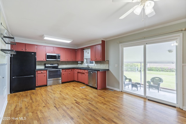 117 Brookfield Dr, Wilmington, NC 28405 - kitchen featuring appliances with stainless steel finishes, red cabinetry, dark countertops, a sink, and ornamental molding