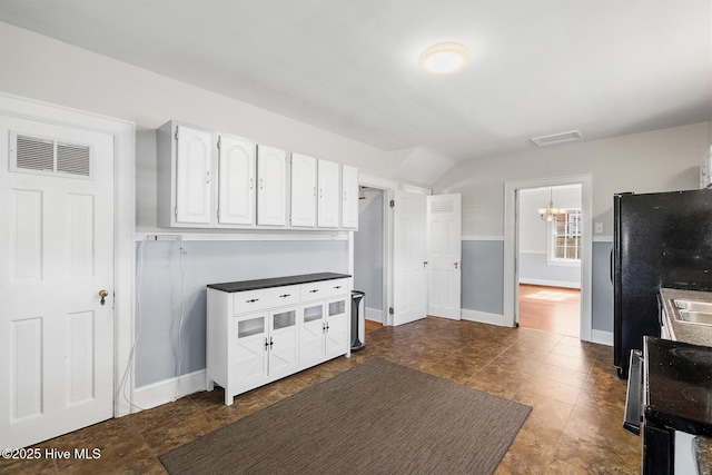 kitchen featuring visible vents, white cabinets, black appliances, and baseboards
