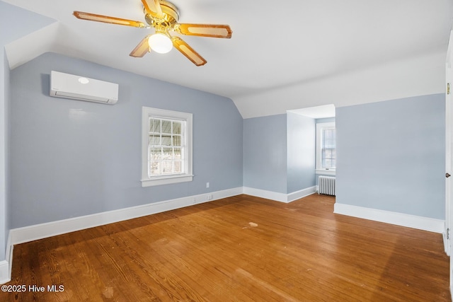 empty room with a wealth of natural light, an AC wall unit, radiator, and lofted ceiling