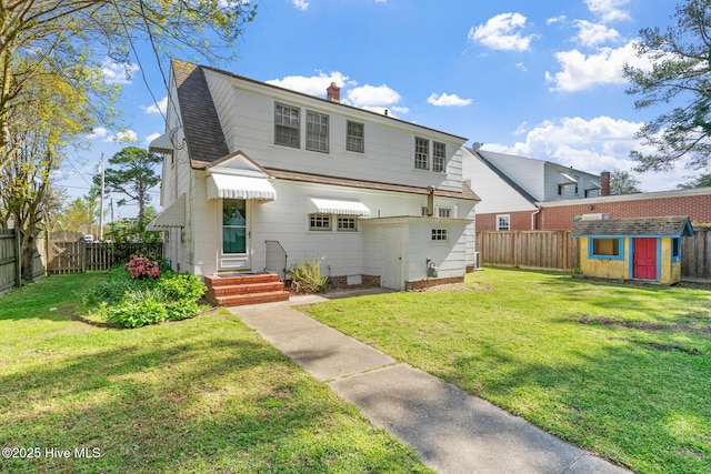 view of front of house featuring an outbuilding, a shed, a fenced backyard, and a front yard