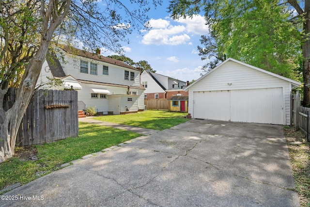 rear view of property with a garage, a yard, fence, and an outbuilding