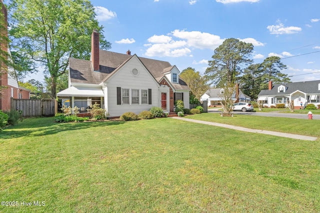 view of front facade with a front yard, fence, and a chimney