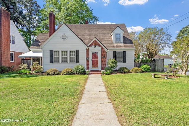 view of front facade featuring a front yard, fence, and brick siding