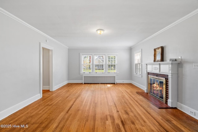 unfurnished living room with radiator, light wood finished floors, ornamental molding, and a brick fireplace