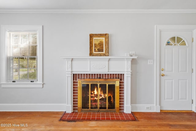 interior details with a fireplace, baseboards, crown molding, and wood finished floors