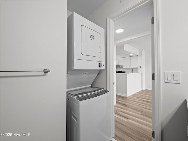 laundry room featuring estacked washer and dryer, light wood-type flooring, and recessed lighting