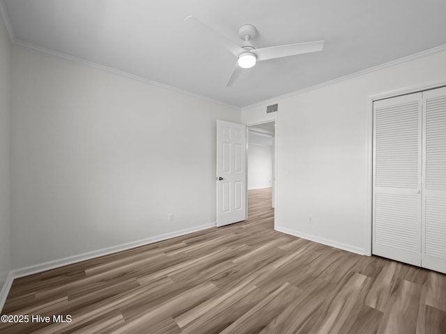 unfurnished bedroom with light wood-style flooring, ornamental molding, a closet, baseboards, and ceiling fan