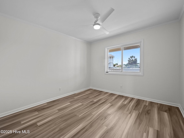 empty room with crown molding, ceiling fan, wood finished floors, and baseboards