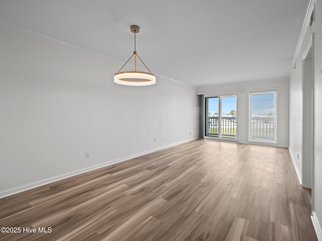 spare room with light wood-style floors, baseboards, and ornamental molding