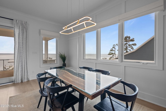 546 S Brightleaf Dr, Minnesott Beach, NC 28510 - dining area featuring a chandelier, wood finished floors, a decorative wall, and a healthy amount of sunlight