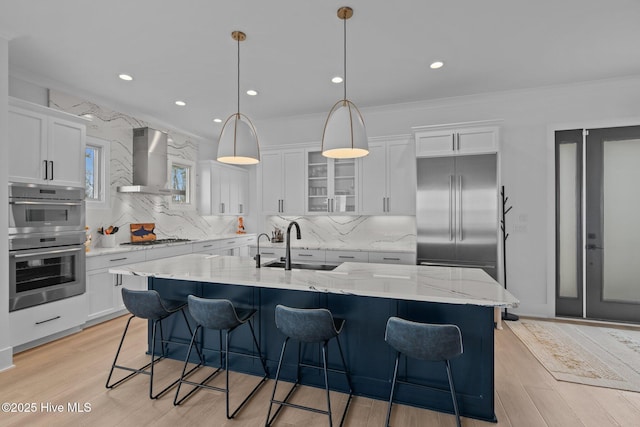 546 S Brightleaf Dr, Minnesott Beach, NC 28510 - kitchen with light wood-style flooring, stainless steel appliances, white cabinetry, a sink, and wall chimney range hood