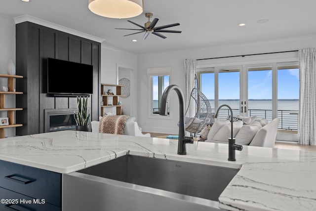 546 S Brightleaf Dr, Minnesott Beach, NC 28510 - kitchen featuring crown molding, a ceiling fan, light stone countertops, dark cabinetry, and open floor plan