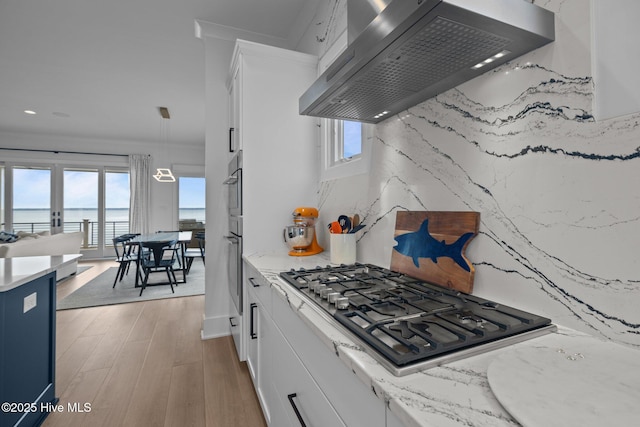 546 S Brightleaf Dr, Minnesott Beach, NC 28510 - kitchen with stainless steel gas cooktop, ventilation hood, backsplash, white cabinetry, and light wood-style flooring