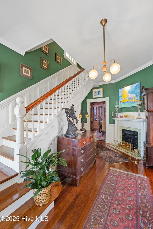211 S 2nd St, Wilmington, NC 28401 - staircase with wood-type flooring, a chandelier, a wainscoted wall, a decorative wall, and ornamental molding